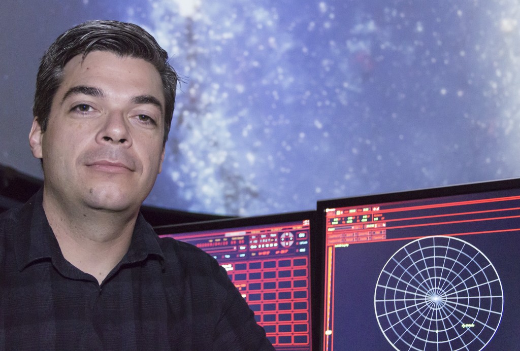 Instructor of Physics and Planetary Sciences, Eric McKenny, sits behind two computer screens that control the planetarium dome in classroom 92044 on Thursday, March 27, 2014. Photo by: Kristen Aslanian