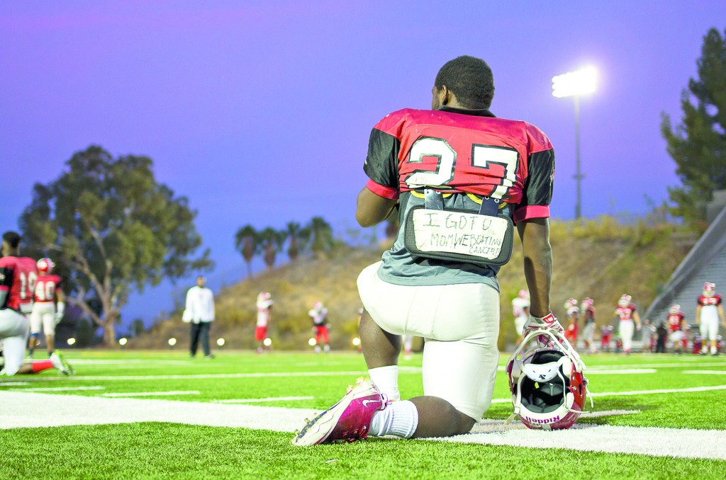 Robert Fowlkes, a running back for Pierce College, takes a knee during practice at John Shephard Stadium of Pierce College in Woodland Hills, Calif., Oct. 22, 2014. Fowlkes' is currently fighting a rare form of cancer in her spine. "I got U mom. We beating cancer," is written on Fowlkes backplate. Photo: Nicolas Heredia