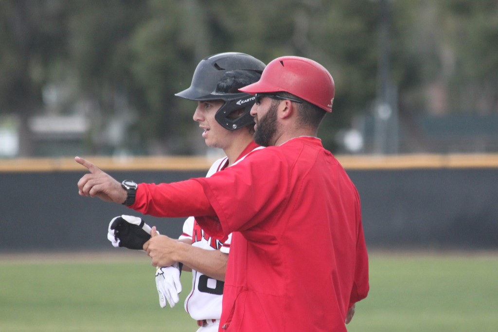 Pierce College assistant baseball coach Eric Bloom stands at first base and leads a player during a game against Ventura College on Tuesday, March 4. Photo by: Megan Moureaux 